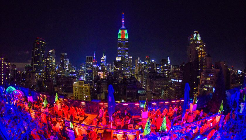 Rooftop scene of Igloo Bar with many people, blue and red lights and igloos