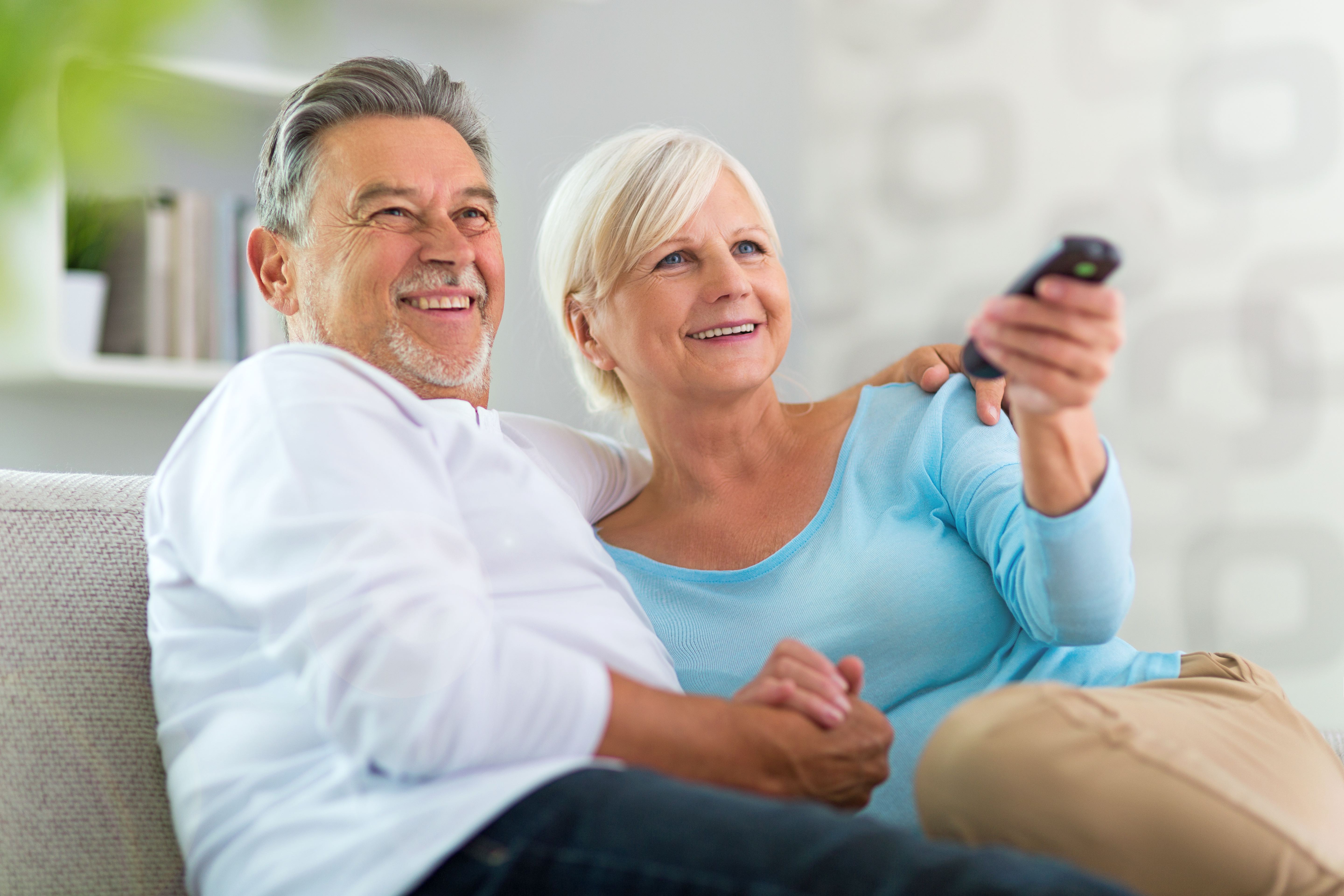 A couple on the couch with the tv remote watching tv