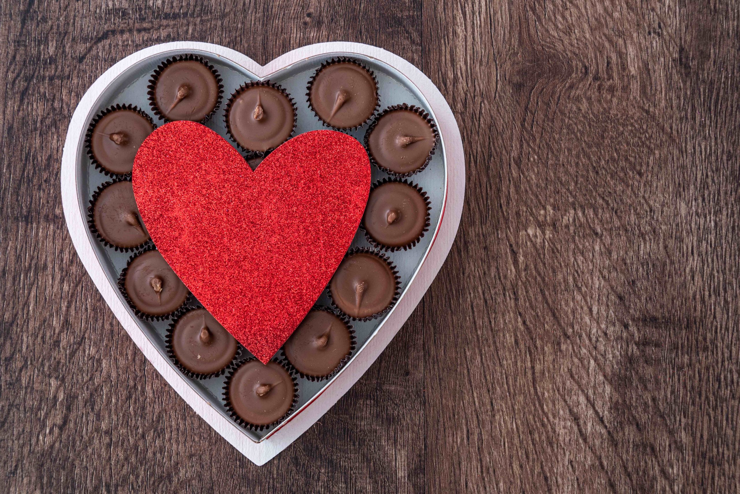 Heart shaped tray with chocolates in it on a wood table
