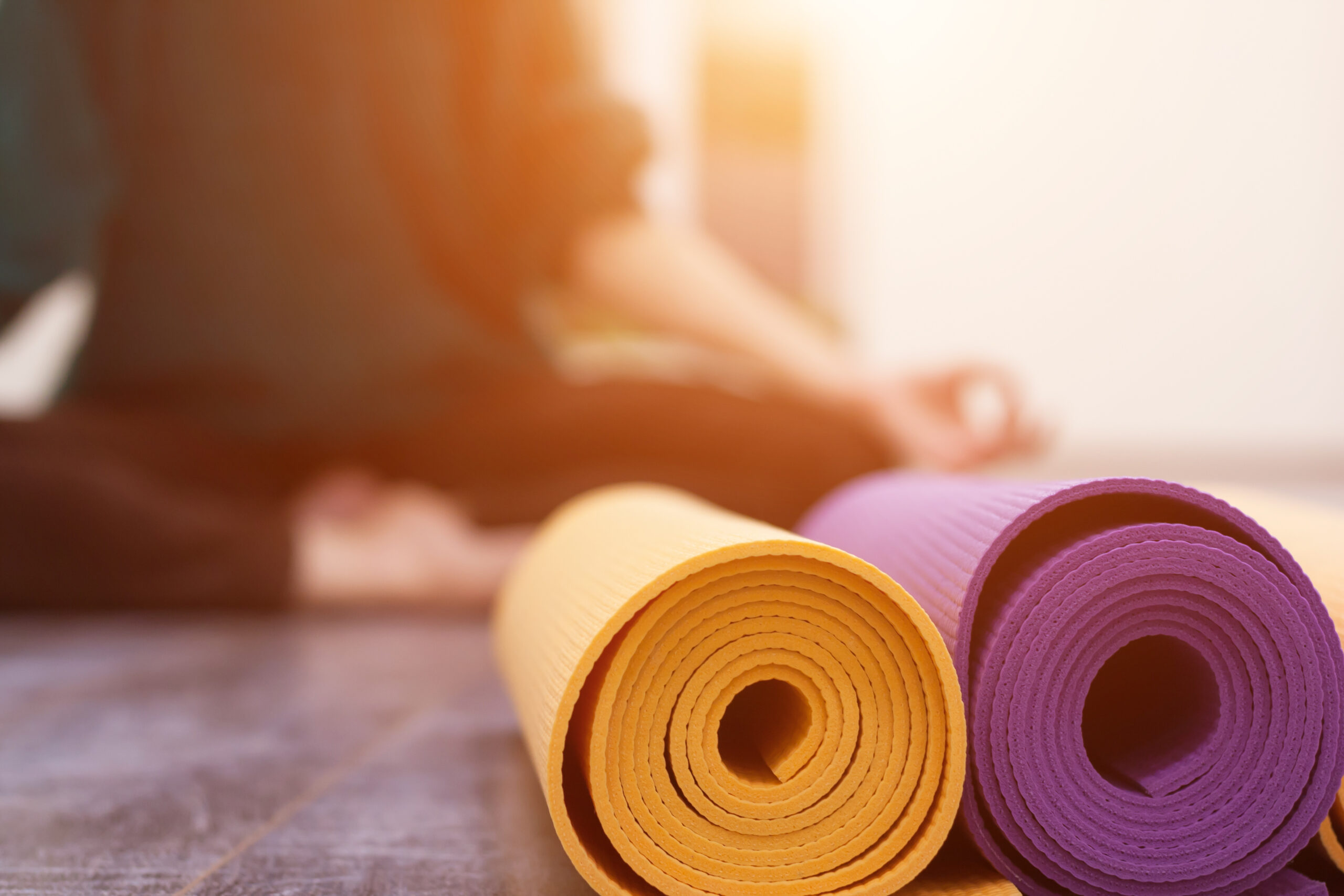 Closeup view of yoga mat and woman sitting in lotus pose on background. Yoga exercising in gym