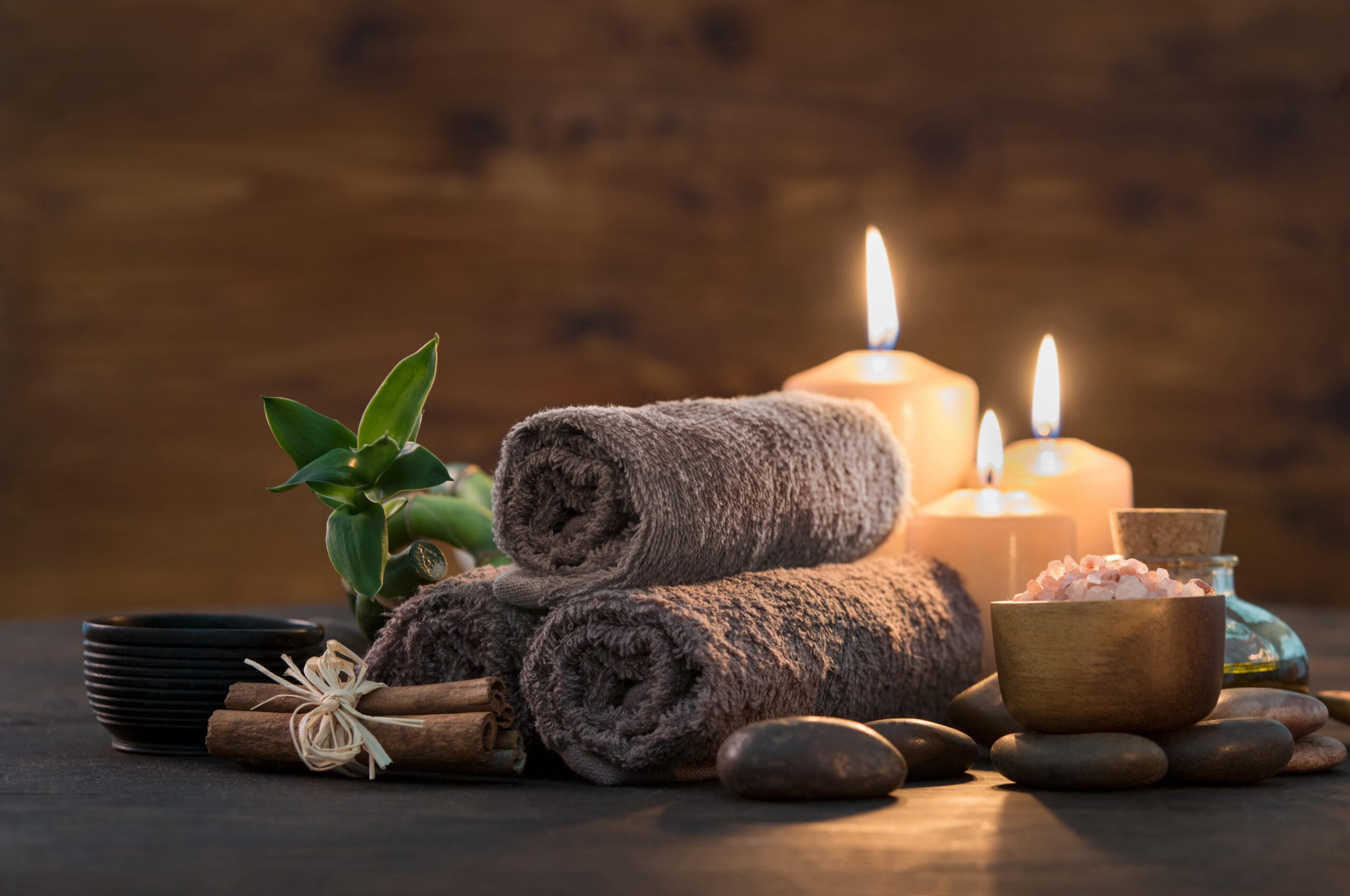 Brown towels with bamboo and candles for relax spa massage and body treatment. Beautiful composition with candles, spa stones and salt on wooden background. Spa and wellness setting ready for beauty treatment.