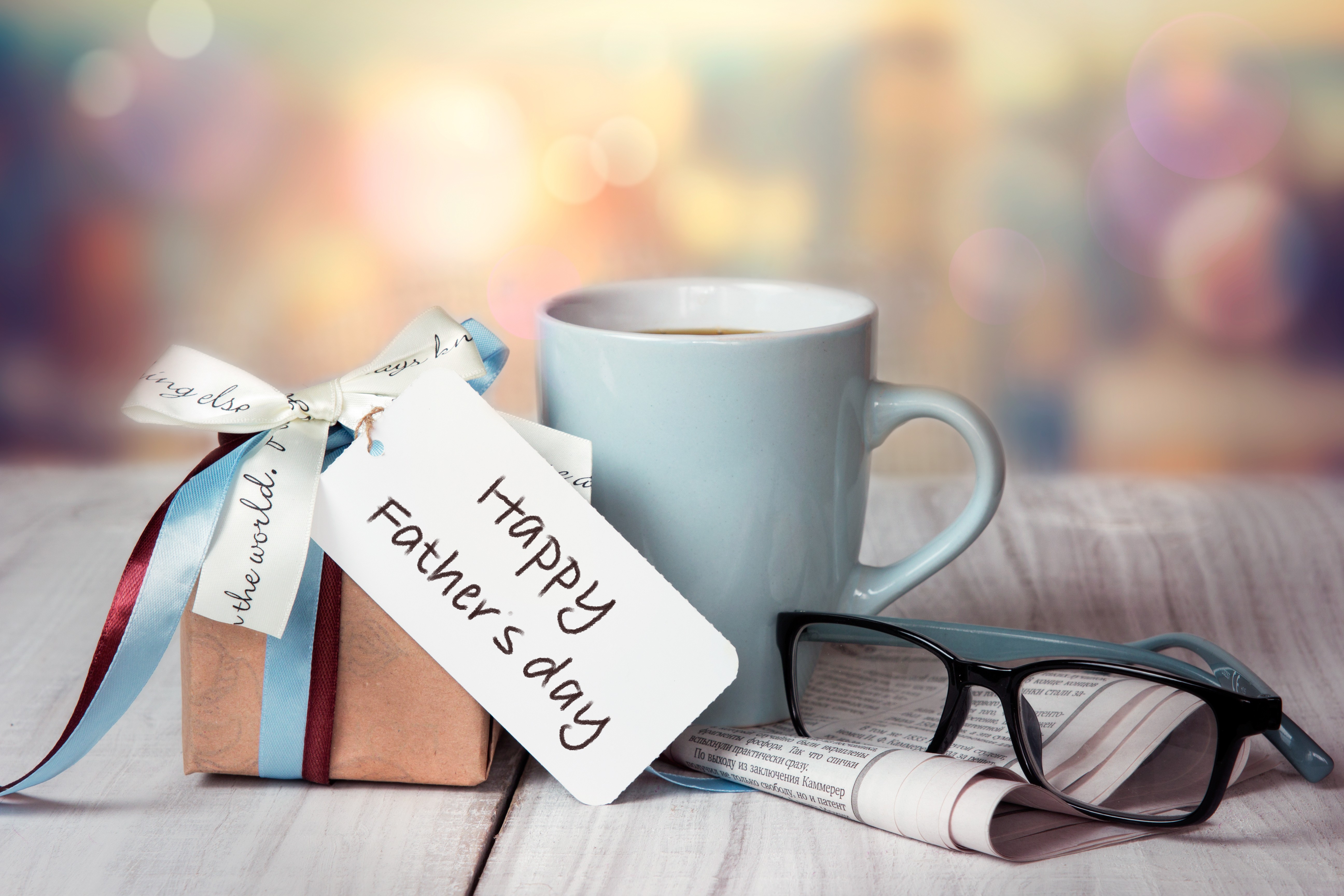 Father's day gift wrapped on wood table with coffee mug, newspaper, and glasses