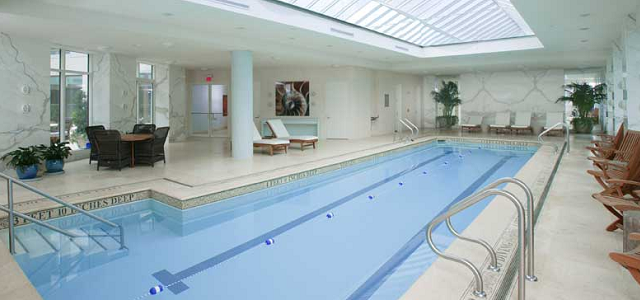 An indoor pool at Glenwood's luxury apartment building with bright decor and blue water.