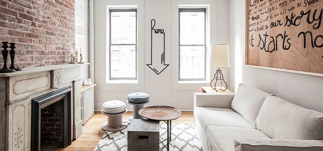 An interior view of a NYC apartment with exposed brick and white furniture.