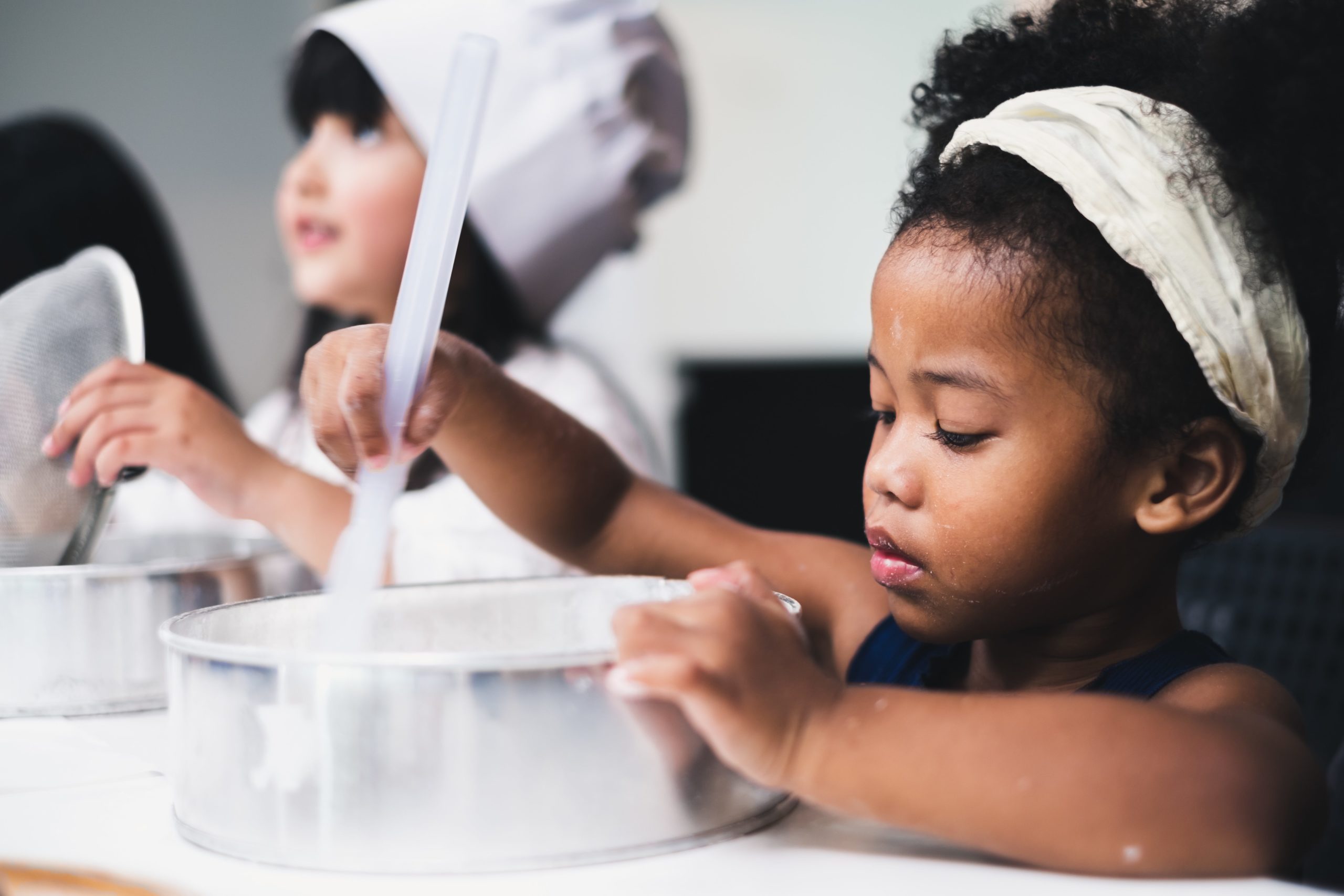 Two children stirring batter in a bowl in cooking class