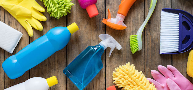Assorted cleaning supplies on a hardwood floor.