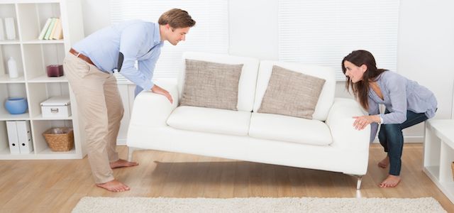 A man and woman picking up a white couch to move.