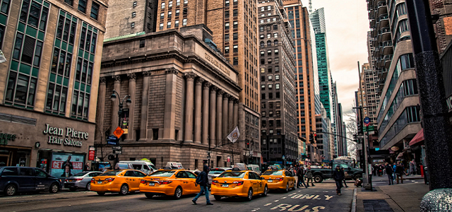 Downtown Manhattan with yellow taxis and tall office buildings.