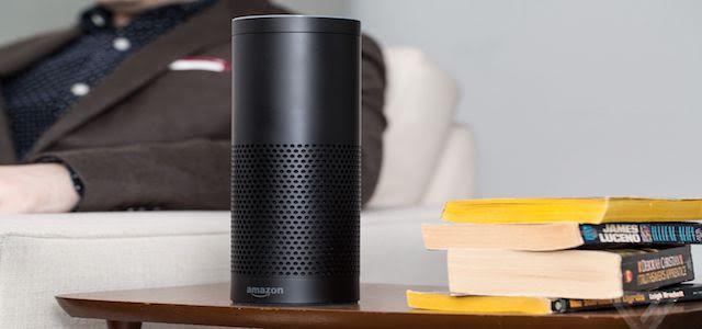 A black Amazon Echo sitting on a brown wooden table.