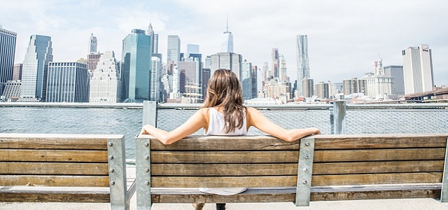 woman sitting on park bench looking at NYC timeline