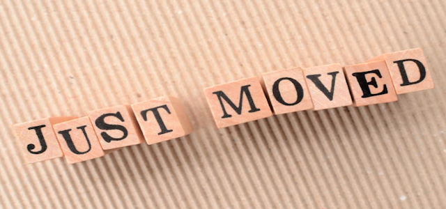 "Just Moved" wooden blocks on a tan background.