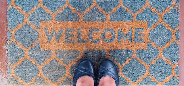 A light blue and tan checkered welcome mat at a front door.