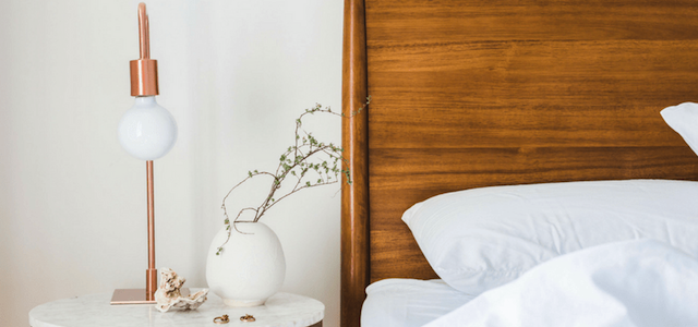 A bedroom decorated with neutral colors and wooden headboard.