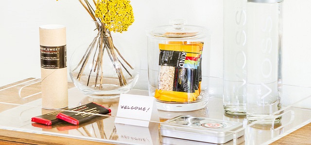 A welcome tray for apartment guests with snacks, fresh flowers, and water.