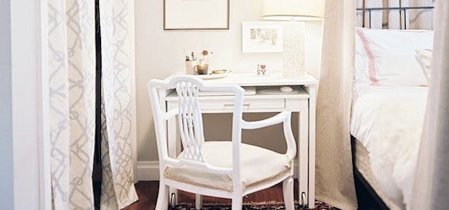 A dual-use vanity and night stand next to a bed.