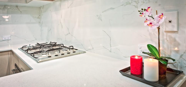 A white luxury kitchen with marble backsplash.