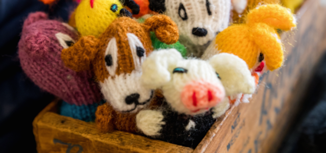 A wooden crate of colorful woven dog toys.