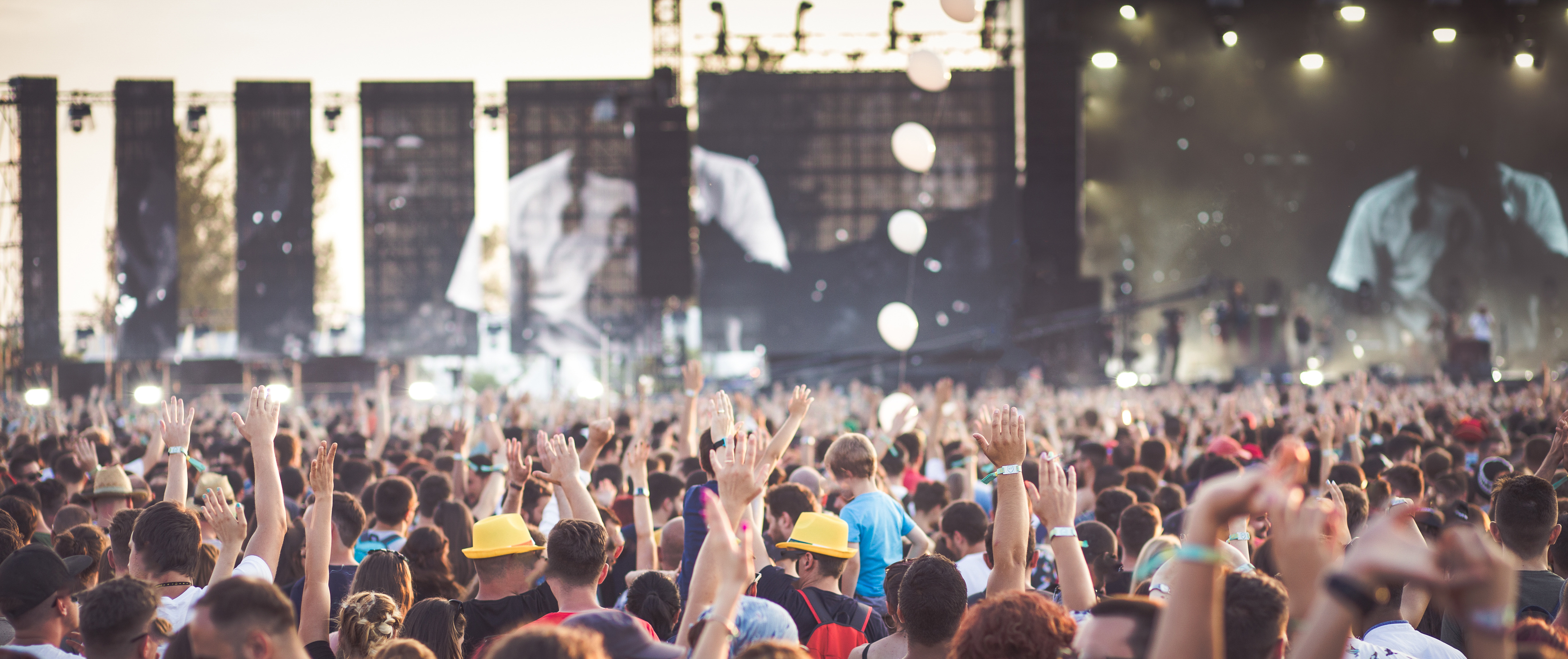 Group of young adults attending a concert cheering with raised hands