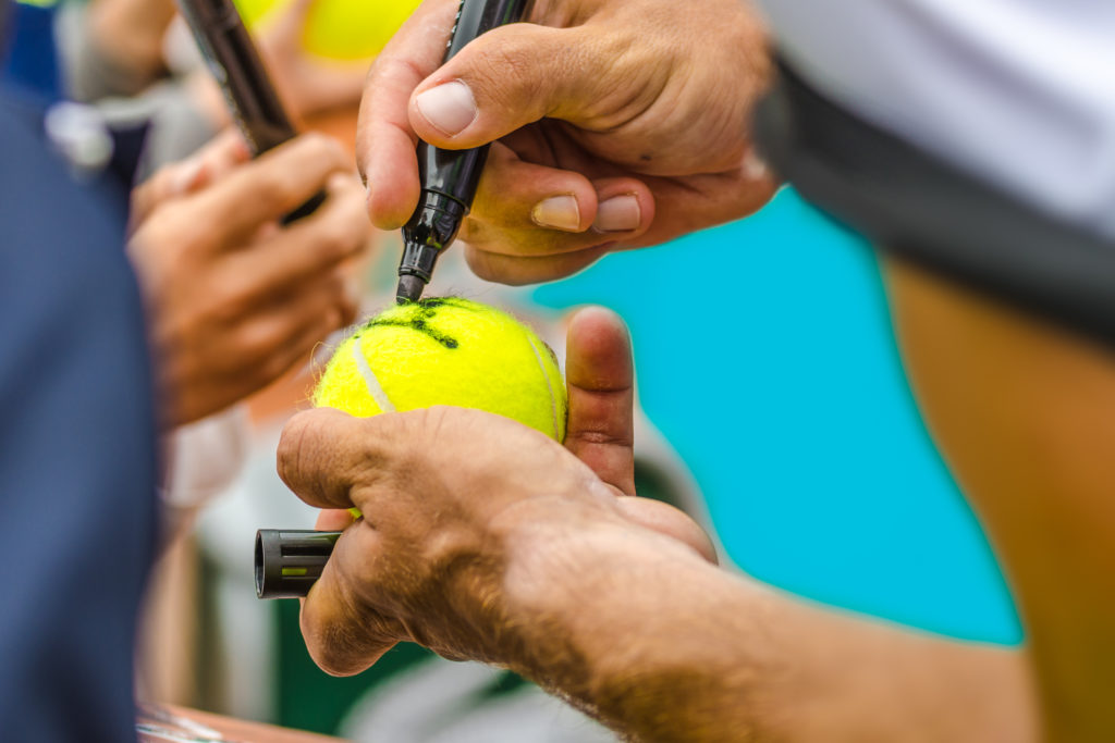 person autographing tennis ball