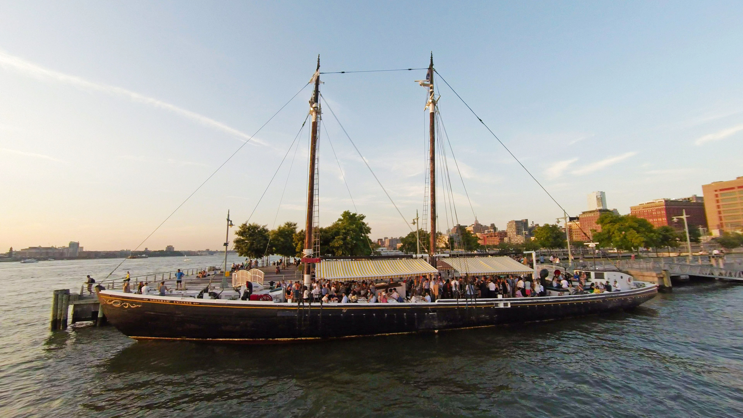 Docked sailboat with a bar that people are drinking at. 