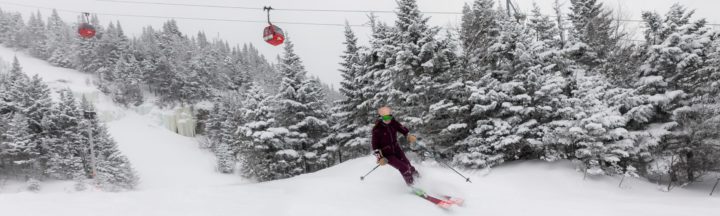 Person skiing down a mountain with a chair lift in the background