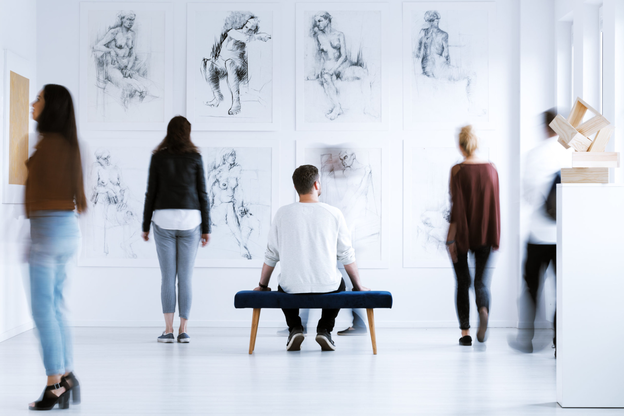 A group of people at an art gallery observing the sketches on display