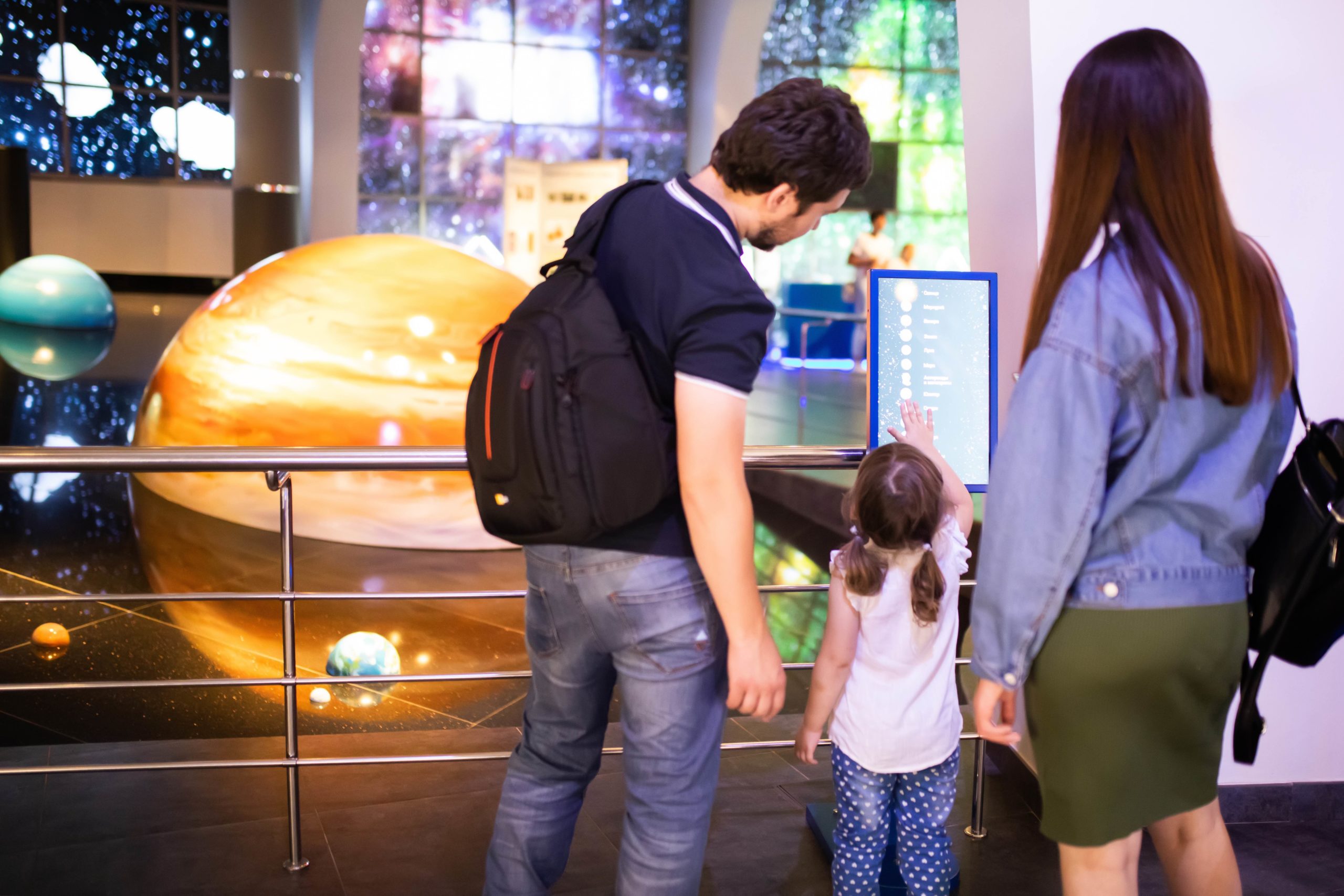 A family observing a planet display at a planetarium museum