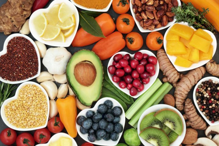 A table featuring healthy food like avocado, lemons, kiwi, peppers, blueberries