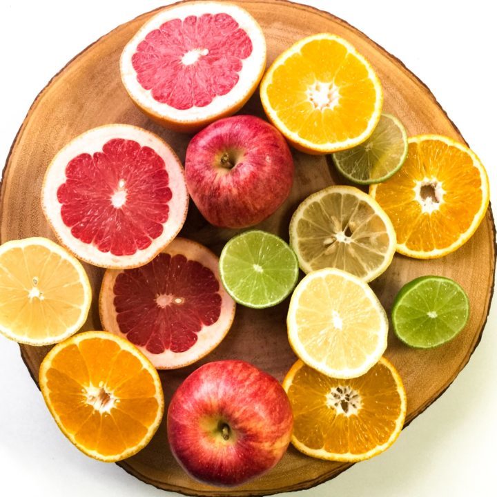 Citrus fruits cut in half and apples on a tray
