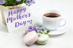 A table with Happy Mother's Day card, flowers, coffee, and macaroons