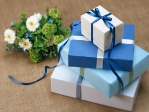 Blue and white gift wrapped boxes with flowers on a wooden surface