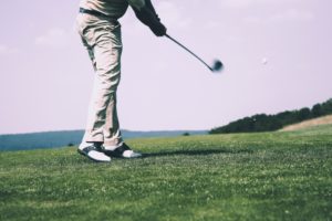 A man hitting a golf club on grass