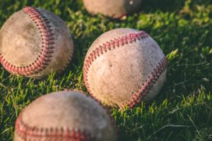 Four baseballs sitting in grass