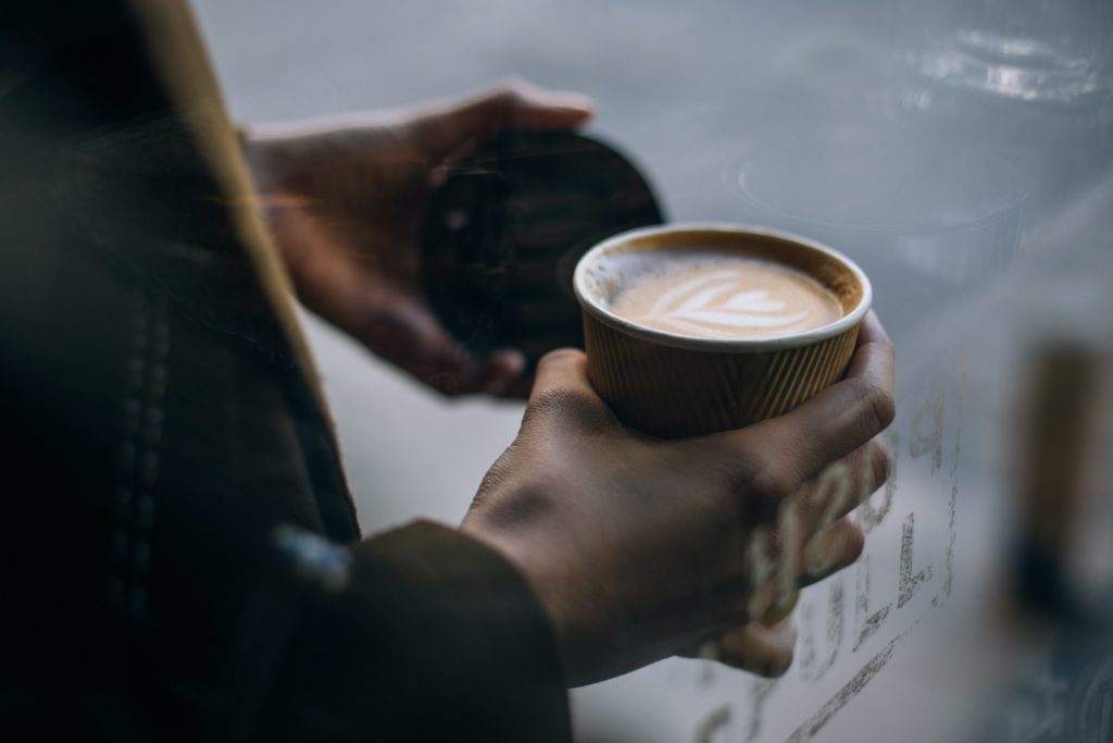 A person carrying a coffee with a heart in the foam