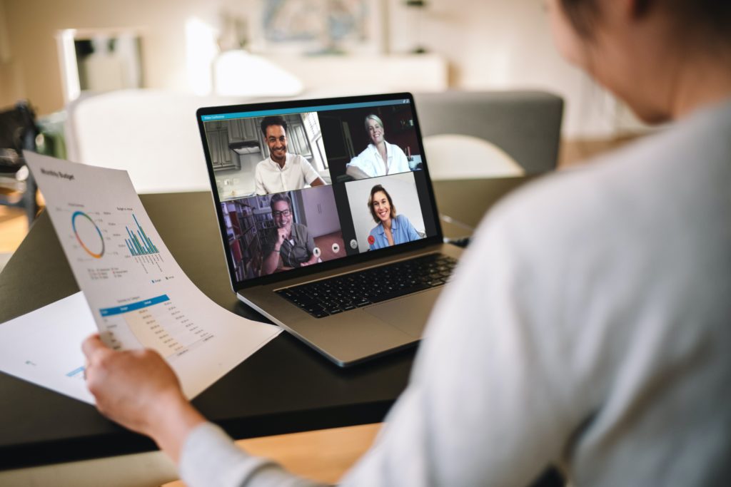 A person working at home with a 4 person online meeting overlooking reports