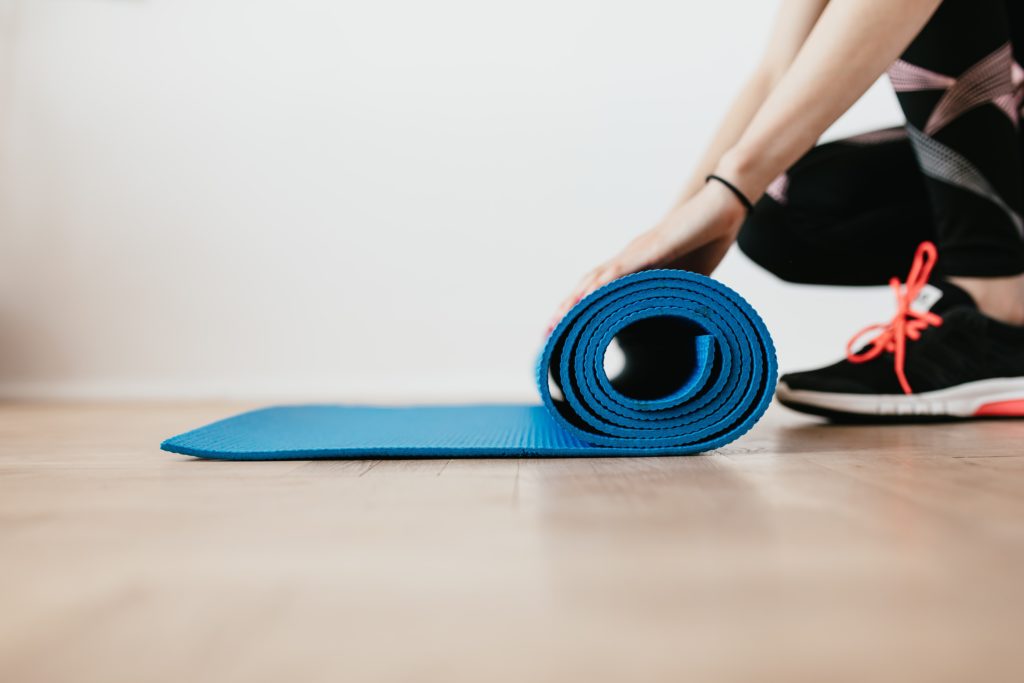 A close up of a woman rolling up an exercise mat in her apartment