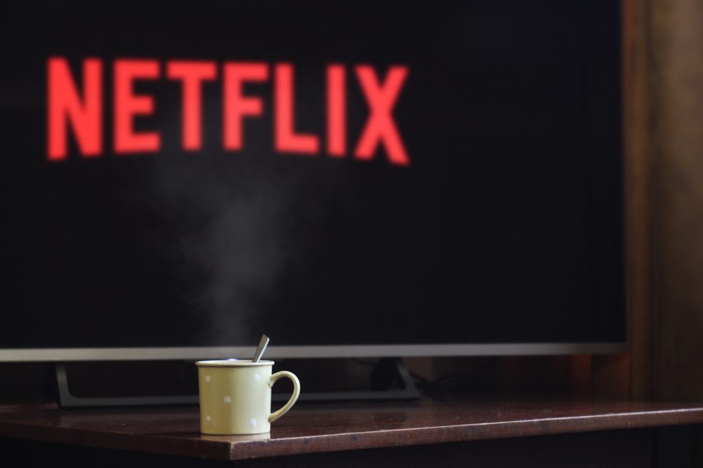A coffee mug sitting infant of a tv screen displaying Netflix