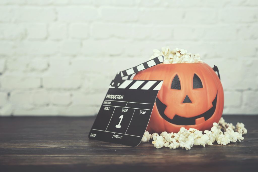 Pumpkin filled with popcorn and a movie roll leaning up against the pumpkin