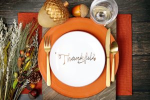 A thanksgiving place setting, orange plate that says thankful
