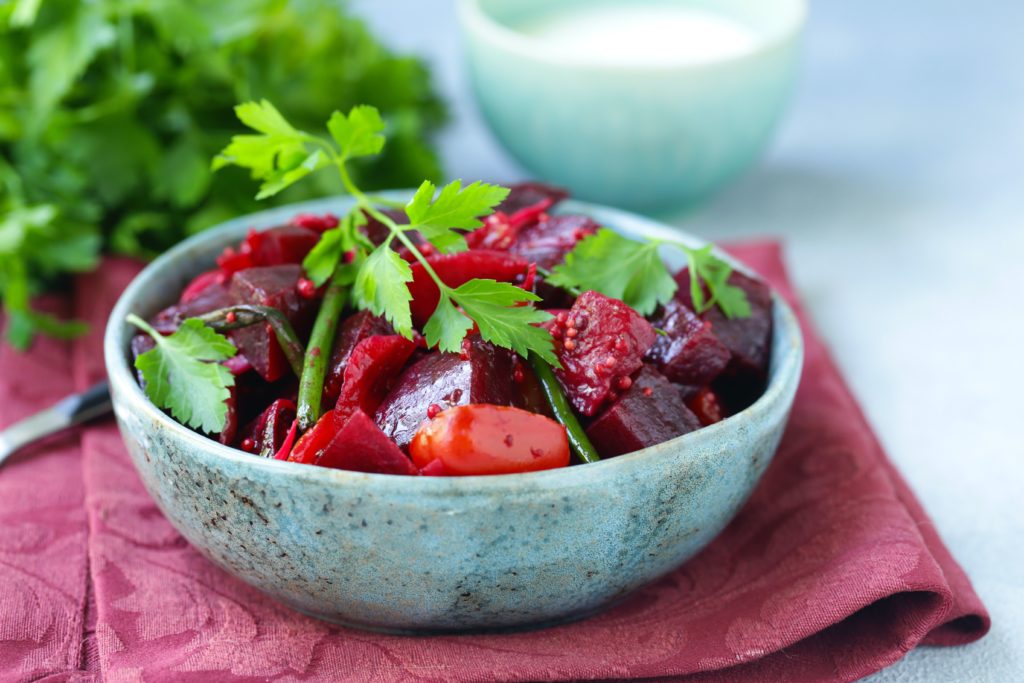 Beet salad and apple salad in a concrete bowl on a red placemat