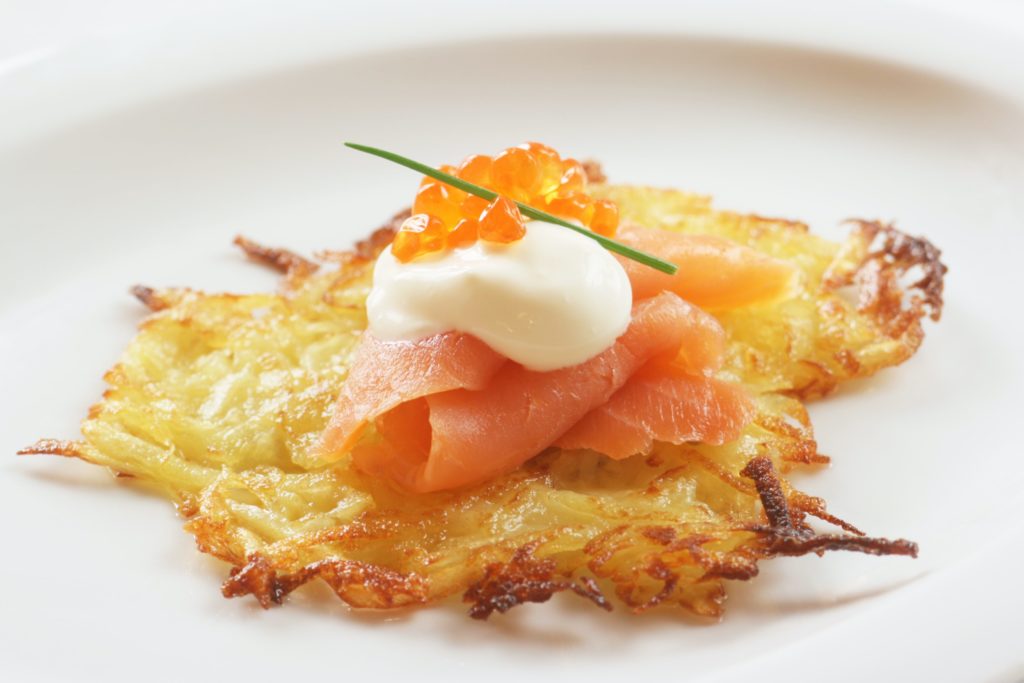 a potato latka topped with sour cream, smoked salmon and salmon roe