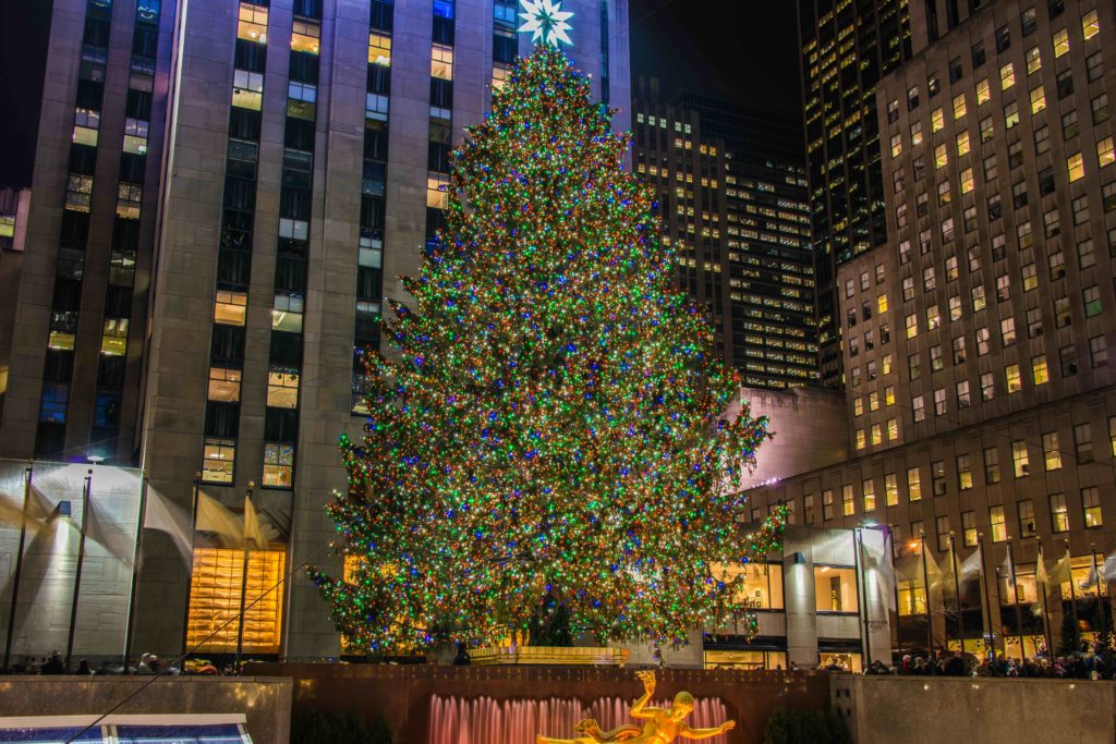 Rockefeller Center Christmas tree lit up with buildings in the background