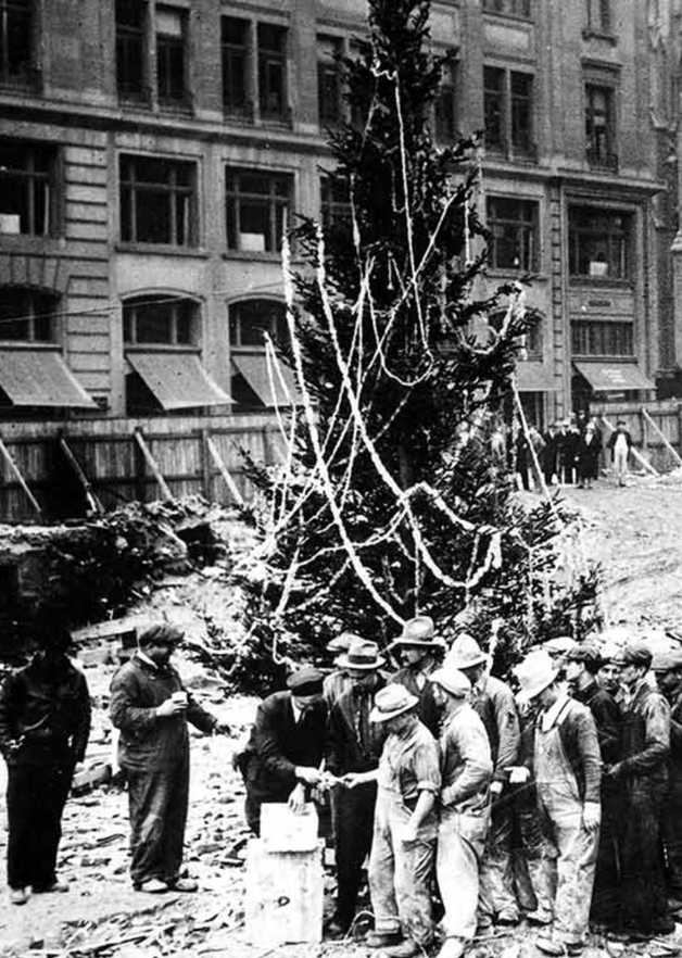 photo from 1931 of first Rockefeller Center Christmas tree with workers lined up in front of it getting their pay checks