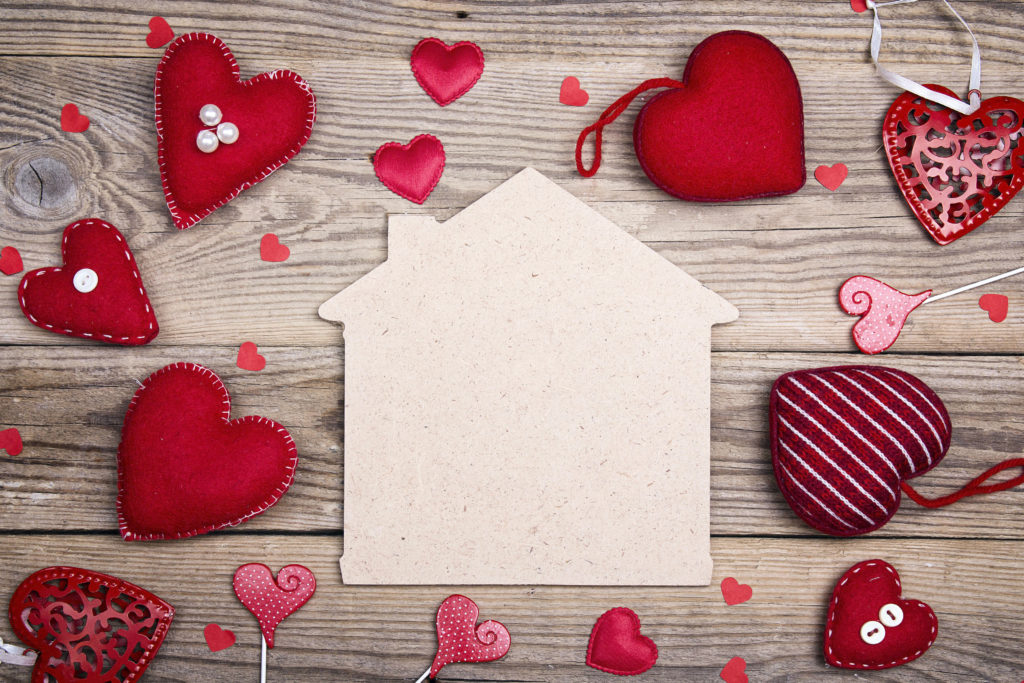 Home symbol with red hearts on wooden background