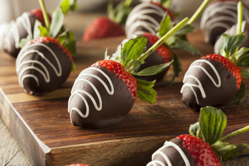 Chocolate covered strawberries on a wooden cutting board