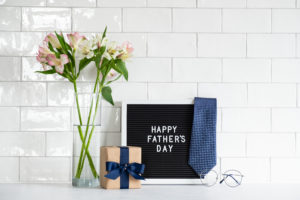 Happy Father's Day sign with flowers, gift, tie and glasses on a kitchen backsplash 