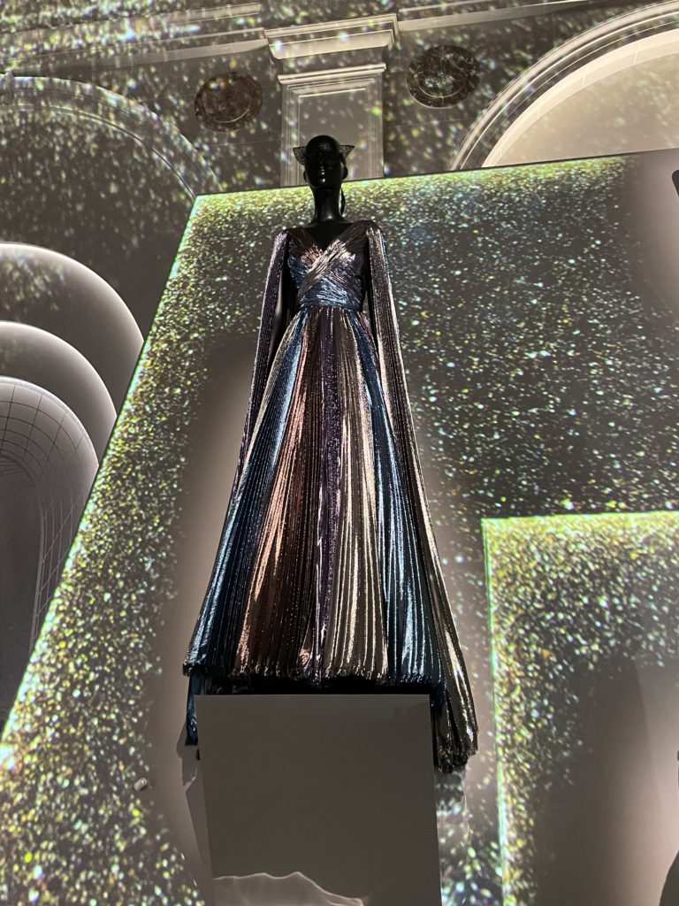 Shimmering Dior dress on a mannequin with a sparkling background
