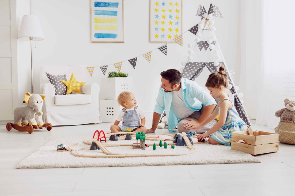 father playing in playroom with his two children
