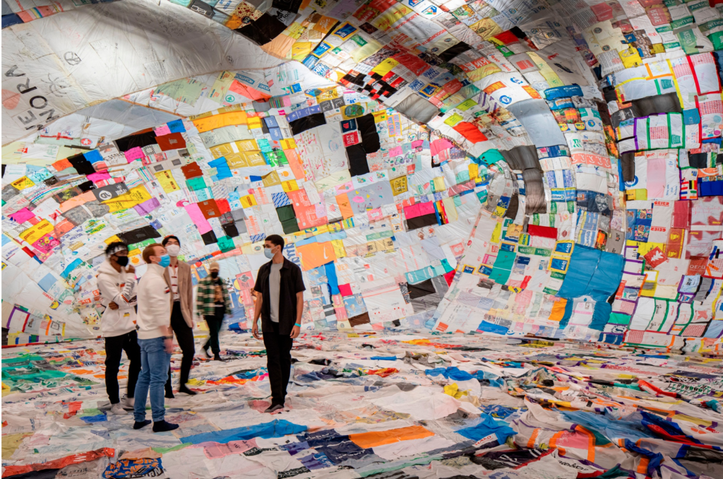 People walking through the exhibits at the shed with colorful material on the wall and floor