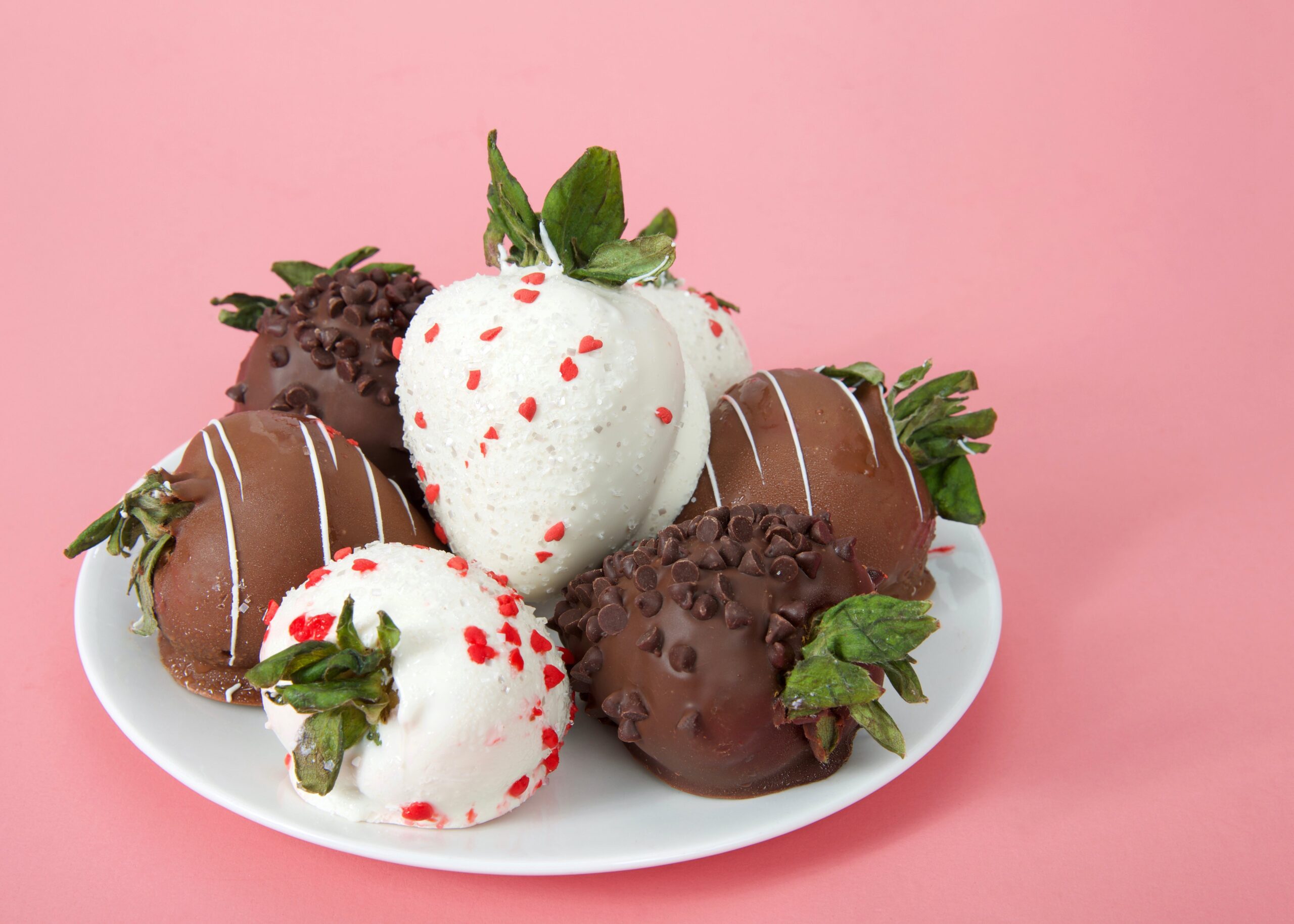 chocolate covered strawberries on a plate with pink background